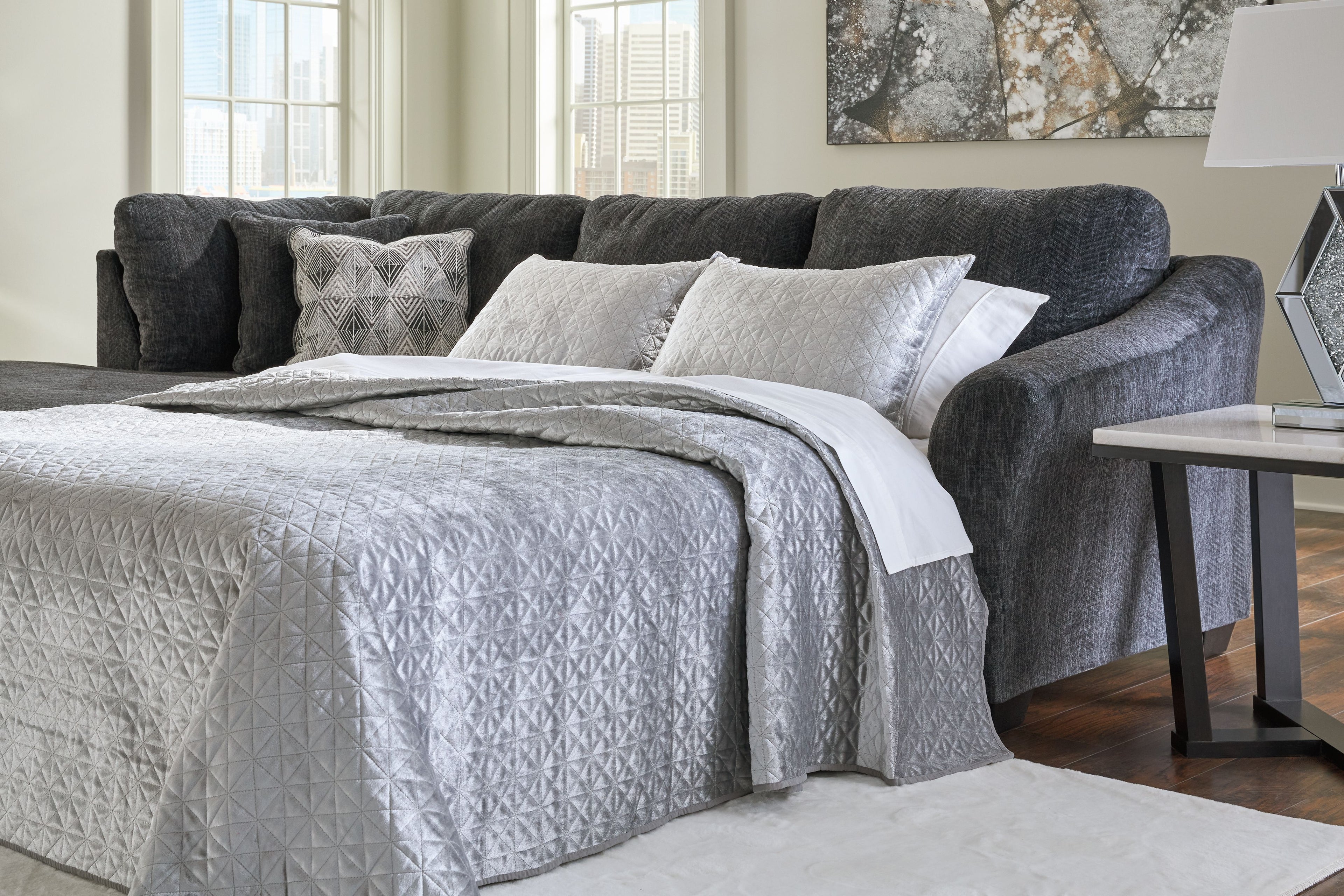 Dark gray sofa sleeper with open bed area and patterned throw pillows