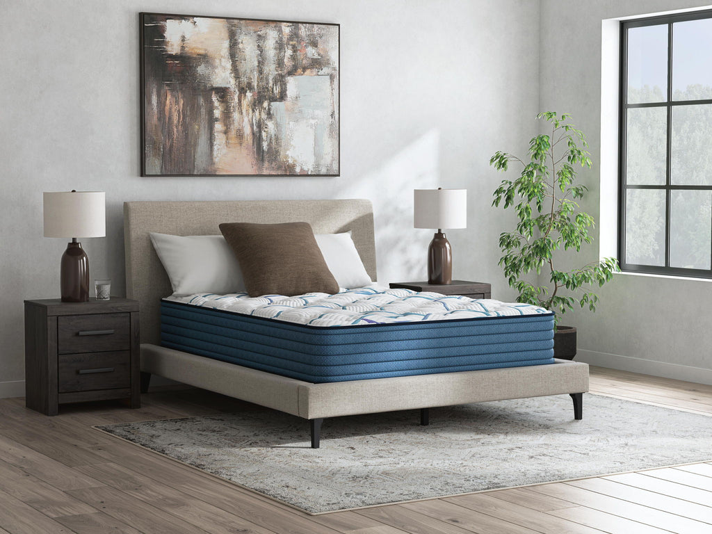 Plush mattress with white patterned cover and blue base on modern bed frame