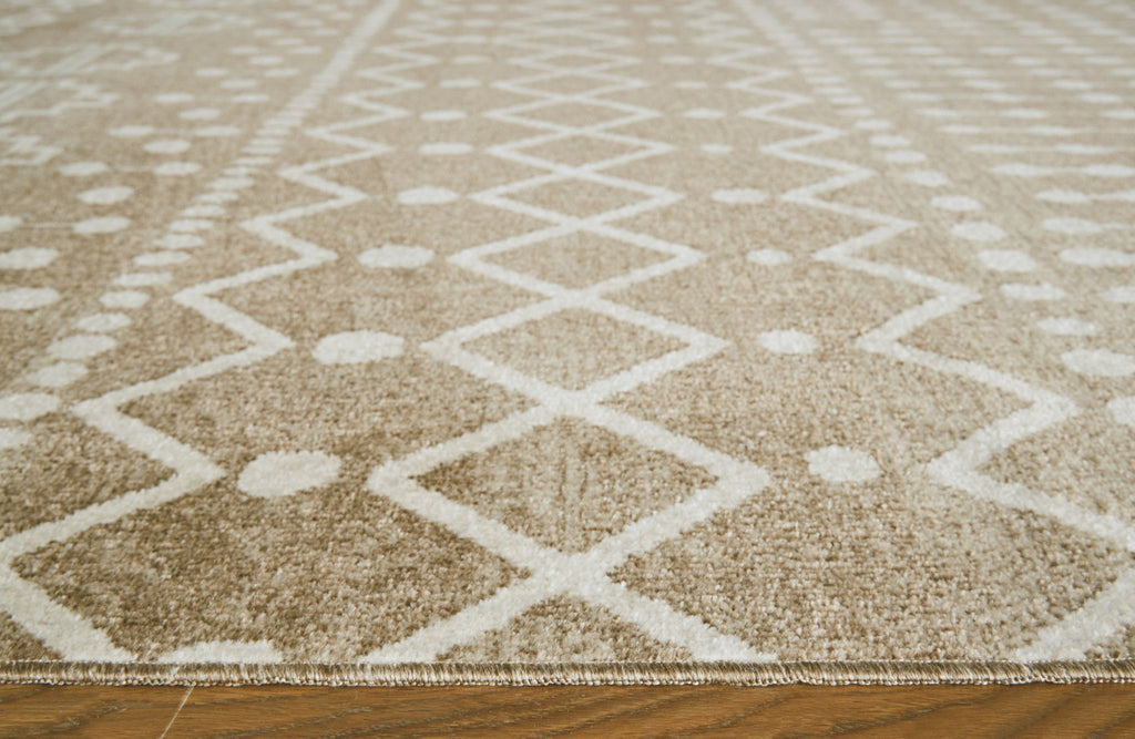 Close-up tan and cream rug pile with diamond and zigzag motif, textured surface