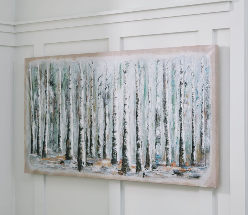 Framed wall art of birch trunks in pale blue, white, and green, mounted on wall