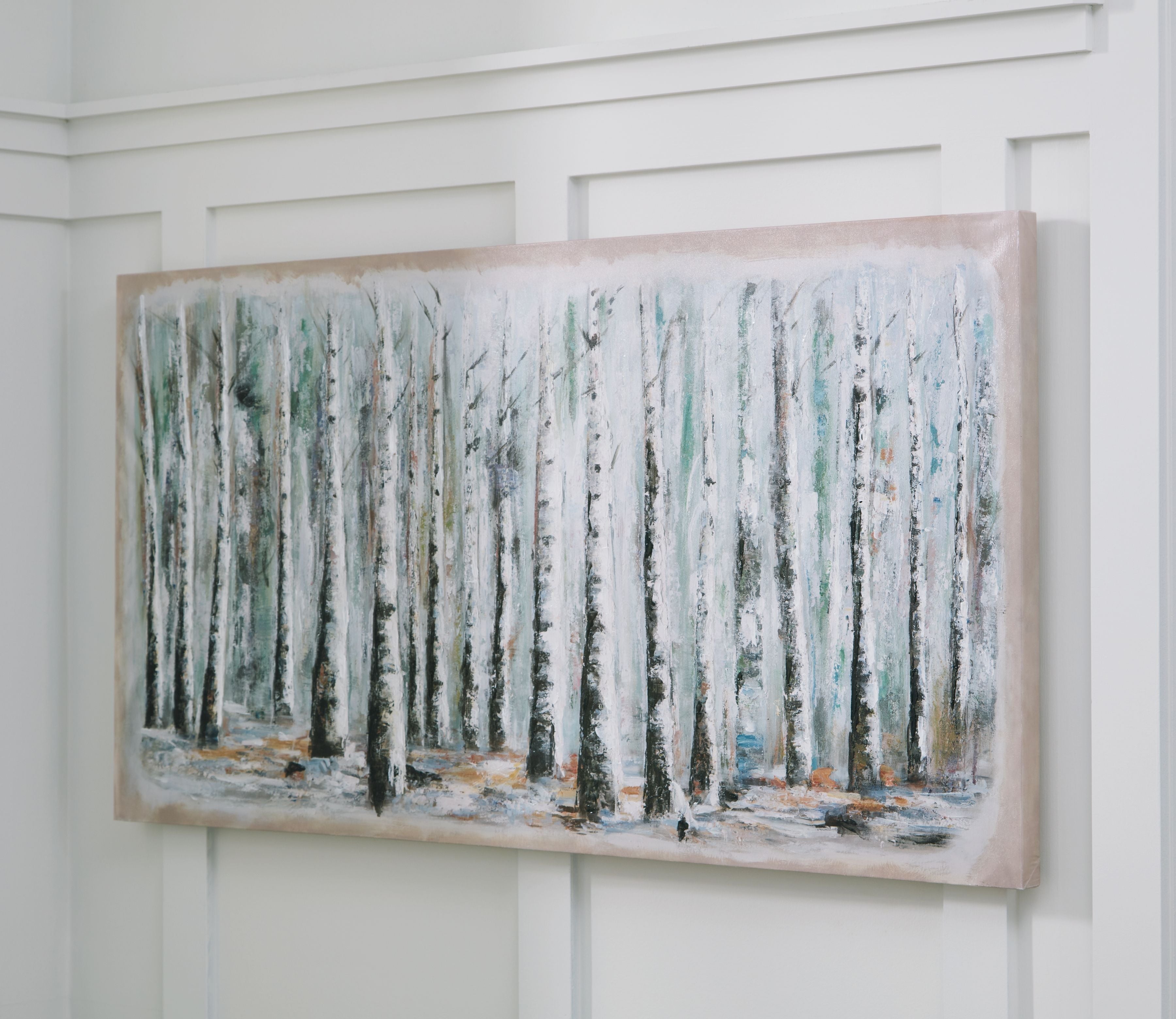 Framed wall art of birch trunks in pale blue, white, and green, mounted on wall