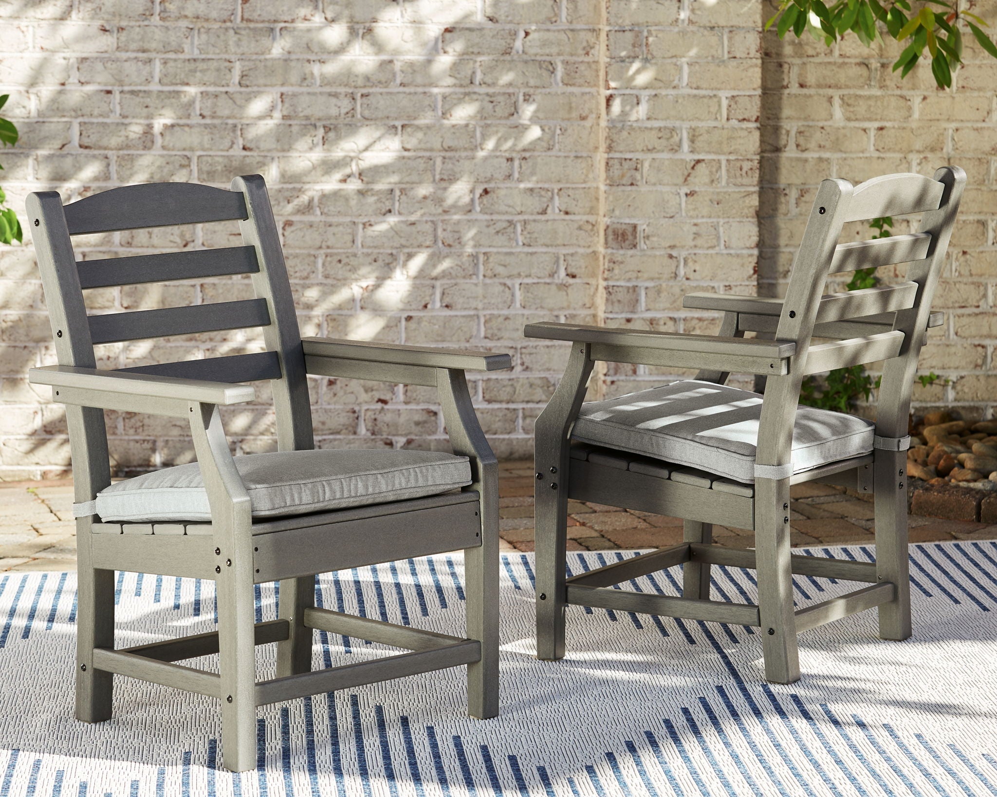 Gray slat-back outdoor chairs with padded seats beside a dining table
