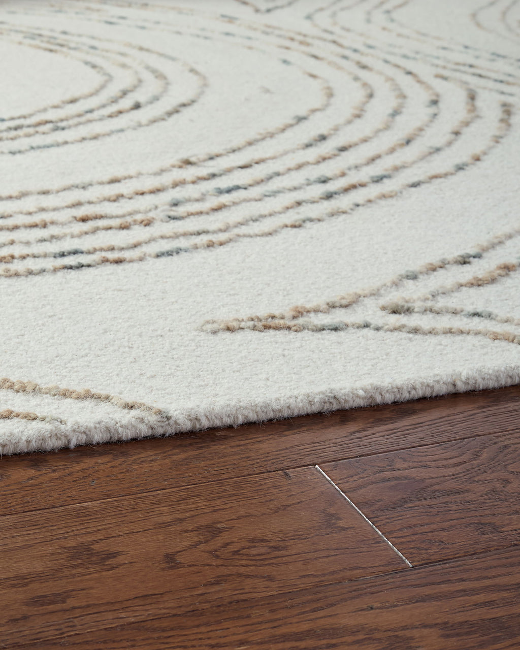 Deenbury rug edge view: off-white pile with beige and gray swirl lines