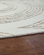 Deenbury rug edge view: off-white pile with beige and gray swirl lines