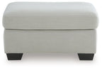 Light gray upholstered ottoman with padded lid and dark square legs