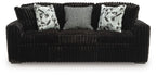 Dark sofa with corduroy fabric and three seat cushions; includes two patterned throw pillows.