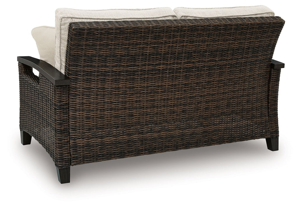 Dark brown wicker loveseat with beige back cushions and armrests