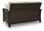 Dark brown wicker loveseat with beige back cushions and armrests