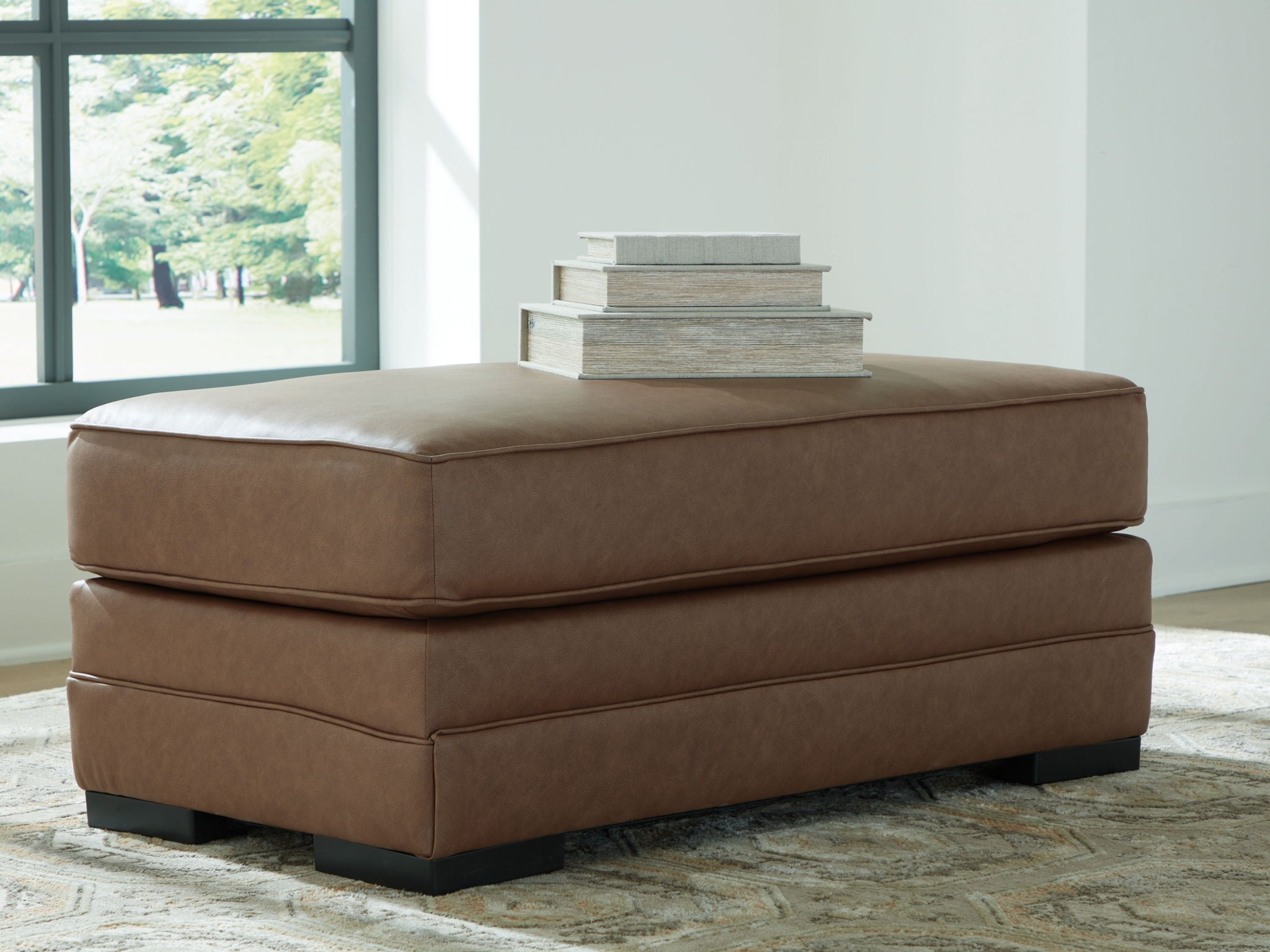 Caramel upholstered ottoman with two-tier design, padded top, and dark legs