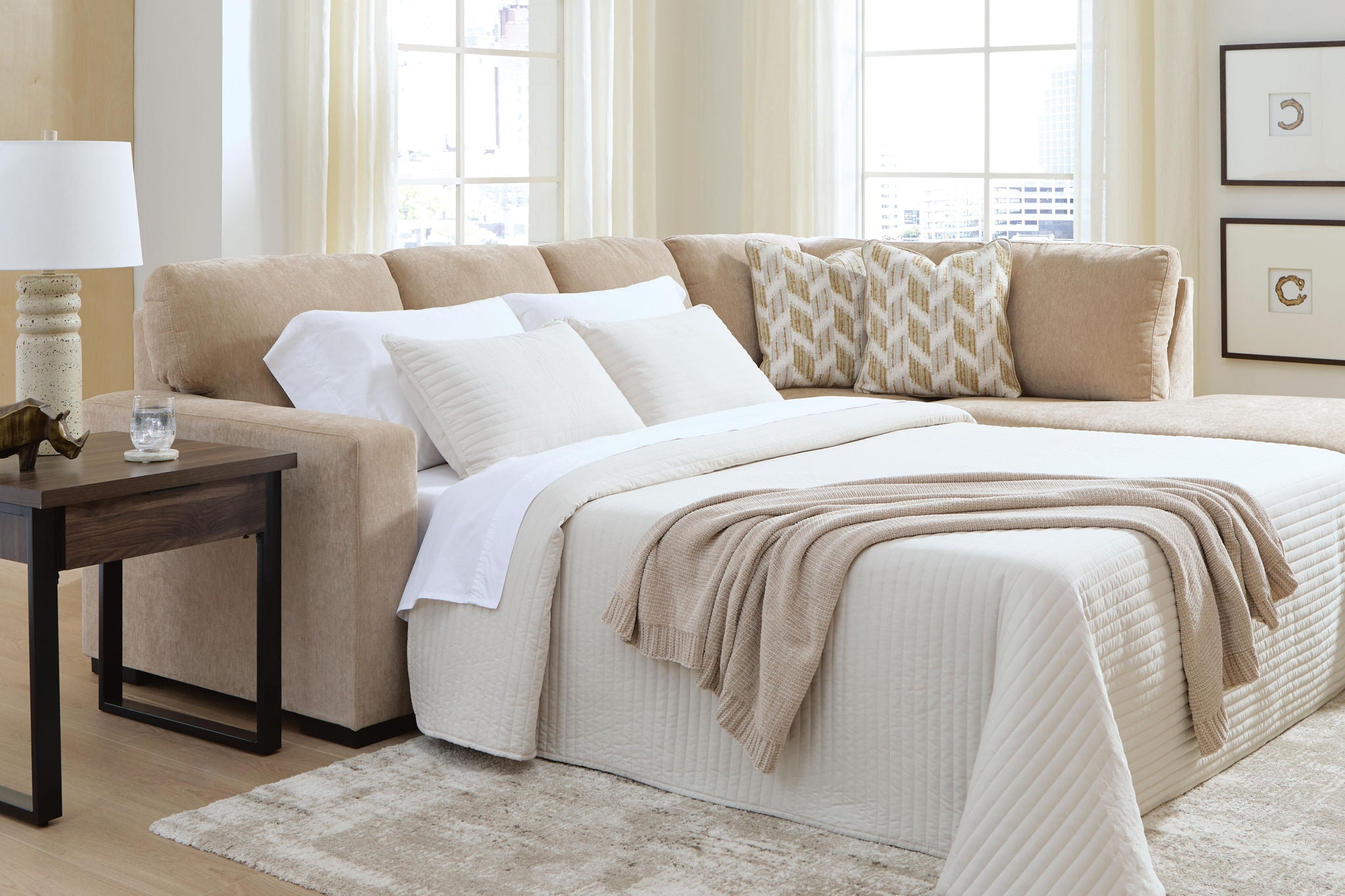 Light brown sleeper sectional with open bed and white pillows, corner chaise seating