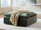 Jade green oversized ottoman with armrest-like sides and folded throw blanket
