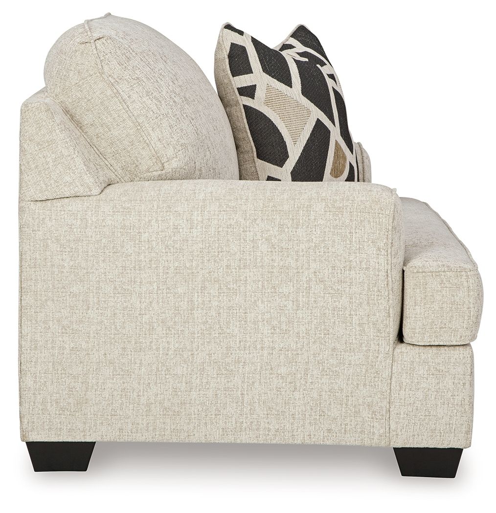 Beige upholstered accent chair with side arm profile and dark geometric pillow