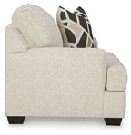 Beige upholstered accent chair with side arm profile and dark geometric pillow