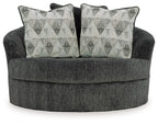 Oversized swivel accent chair in dark gray with two geometric patterned throw pillows