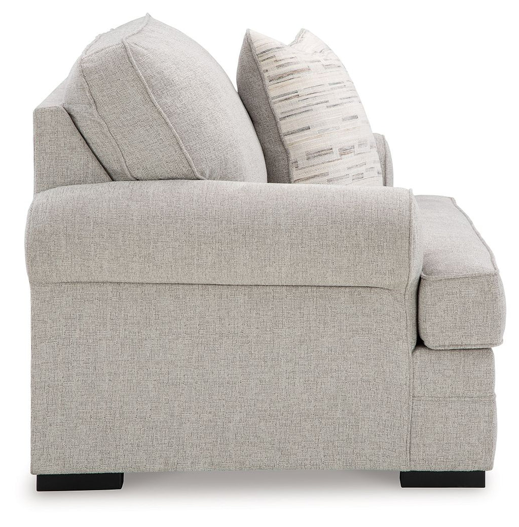 Gray fabric chair with padded arms and stacked throw pillows