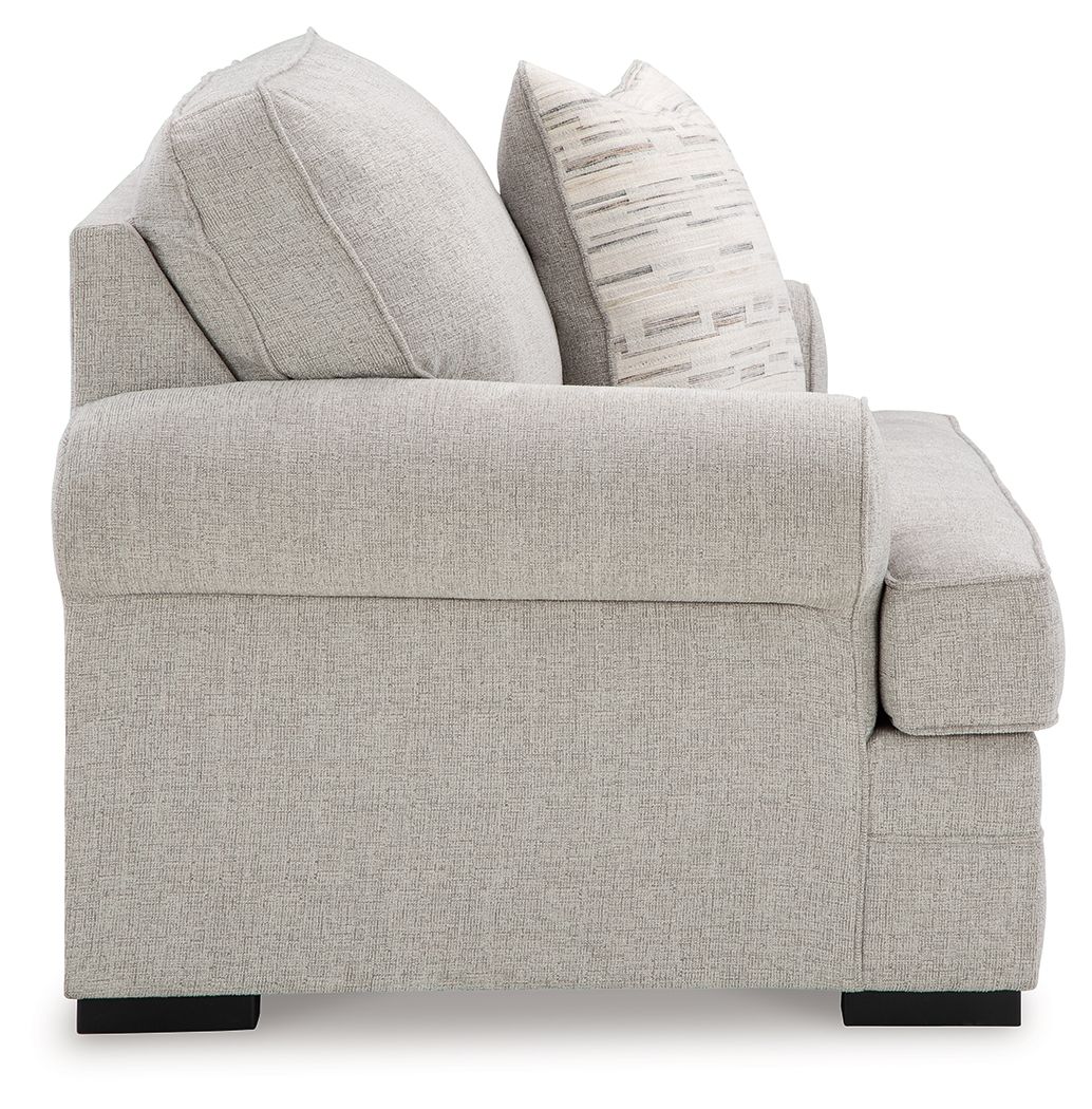 Gray fabric chair with padded arms and stacked throw pillows