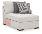 Stone corner chaise with light gray fabric, tufted seat, two accent pillows.