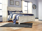 Whitewash bed frame with blue patterned bedding and striped throw