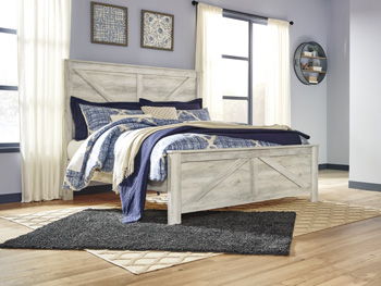 Whitewash bed frame with blue patterned bedding and striped throw