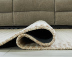 Beige rug showing cut pile texture and stitched edge at folded corner