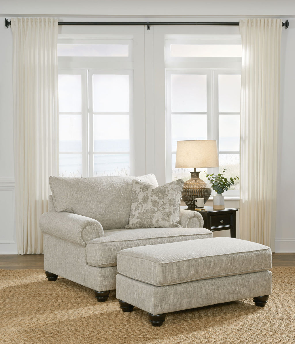 Light gray fabric sofa with matching ottoman and patterned throw pillows