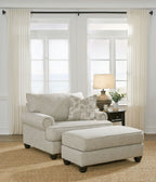 Light gray fabric sofa with matching ottoman and patterned throw pillows