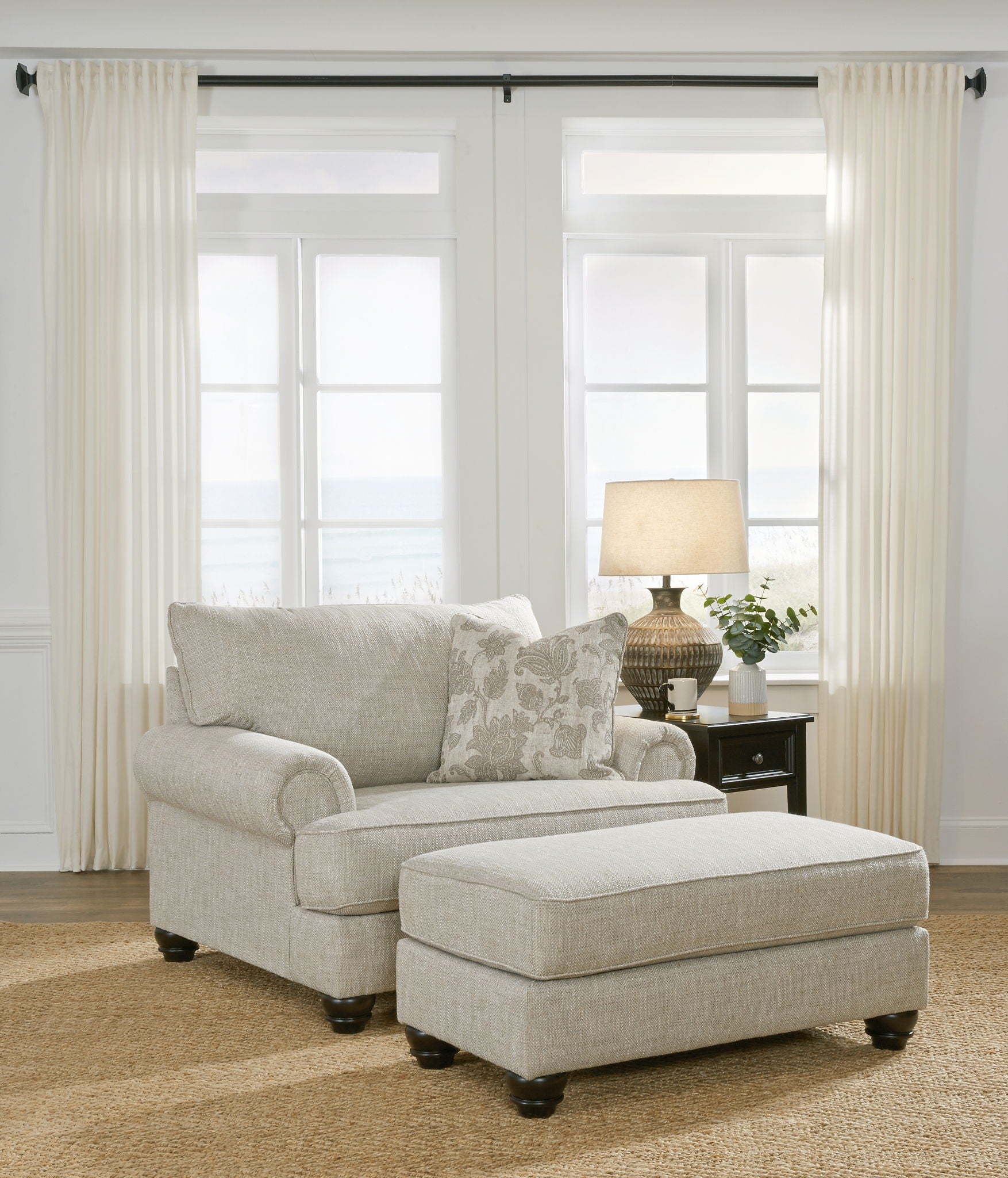 Light gray fabric sofa with matching ottoman and patterned throw pillows