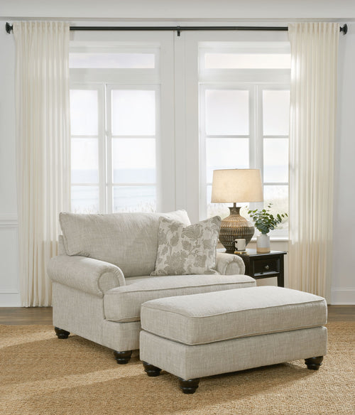 Light gray fabric sofa with matching ottoman and patterned throw pillows
