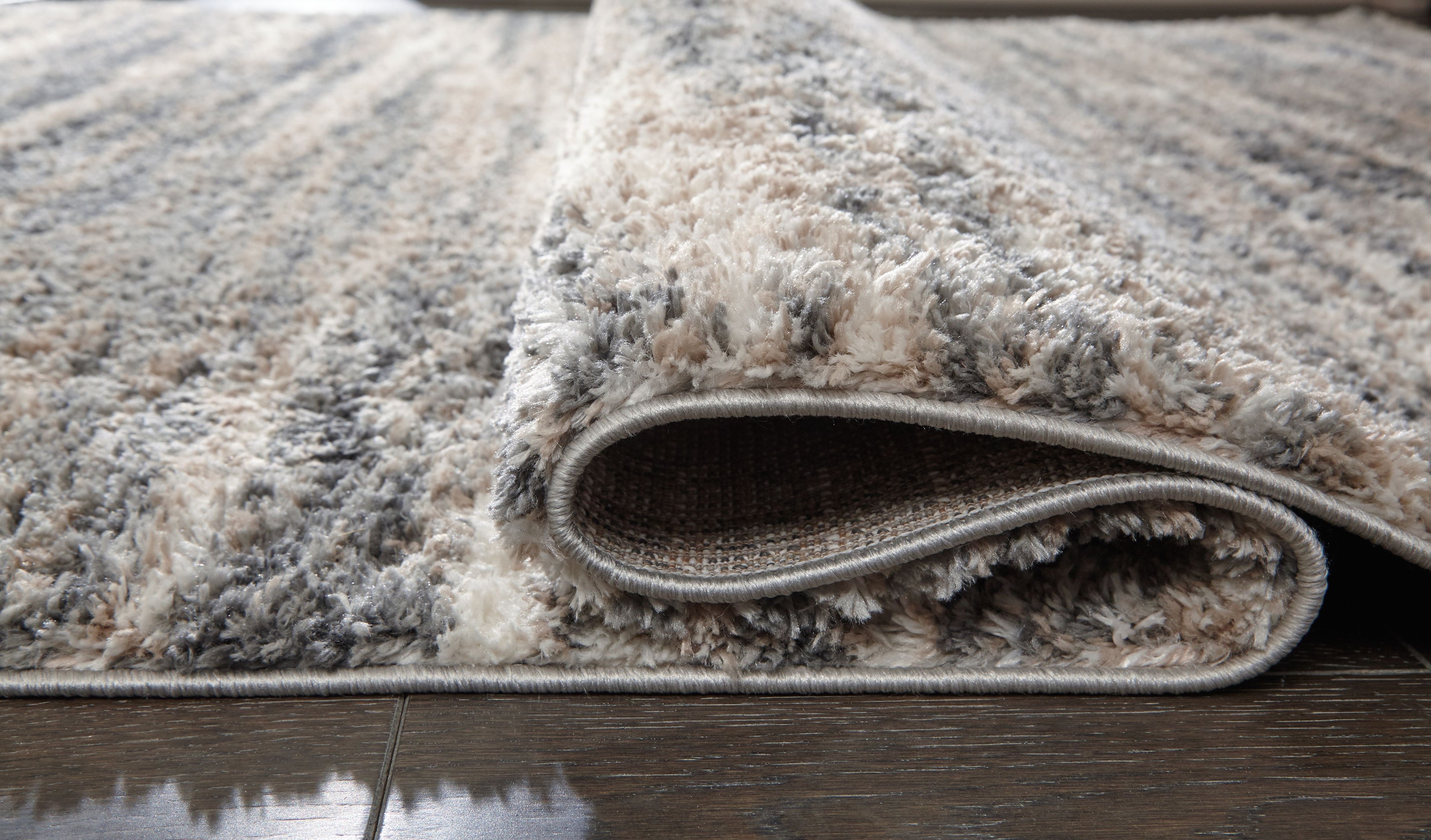 Shag rug edge with rolled pile and visible woven backing