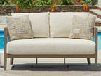 Loveseat with cushion on dark brown frame, light beige seat and two patterned pillows