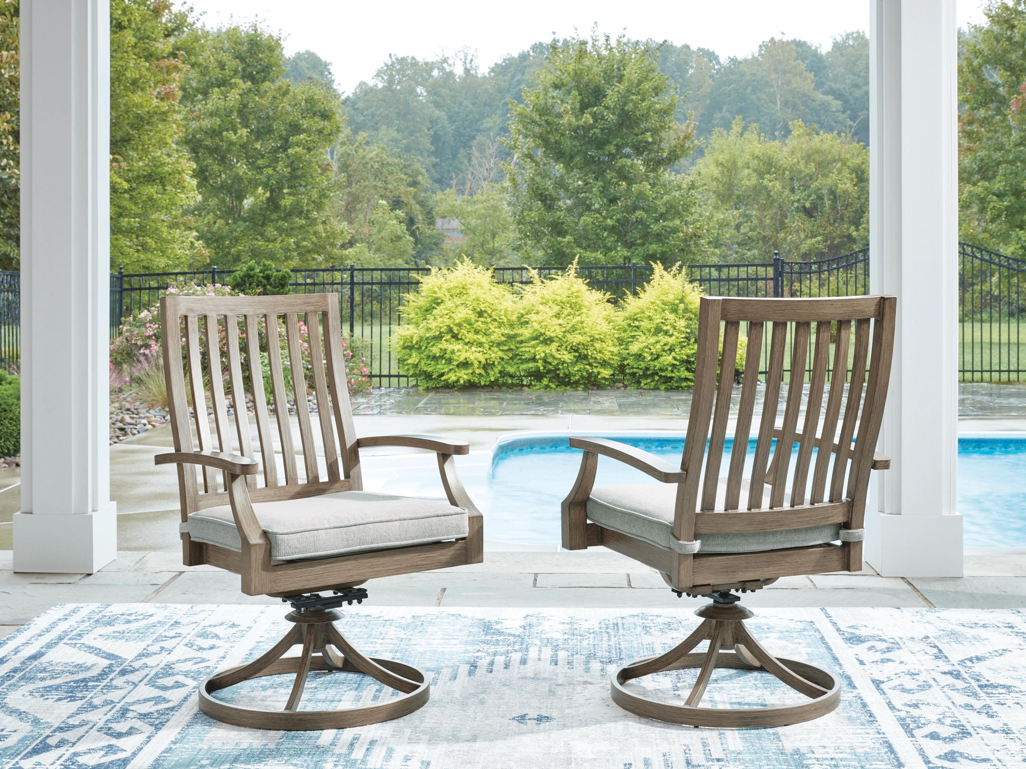 Set of 2 swivel patio chairs with light gray cushions, brown slatted backs and round bases