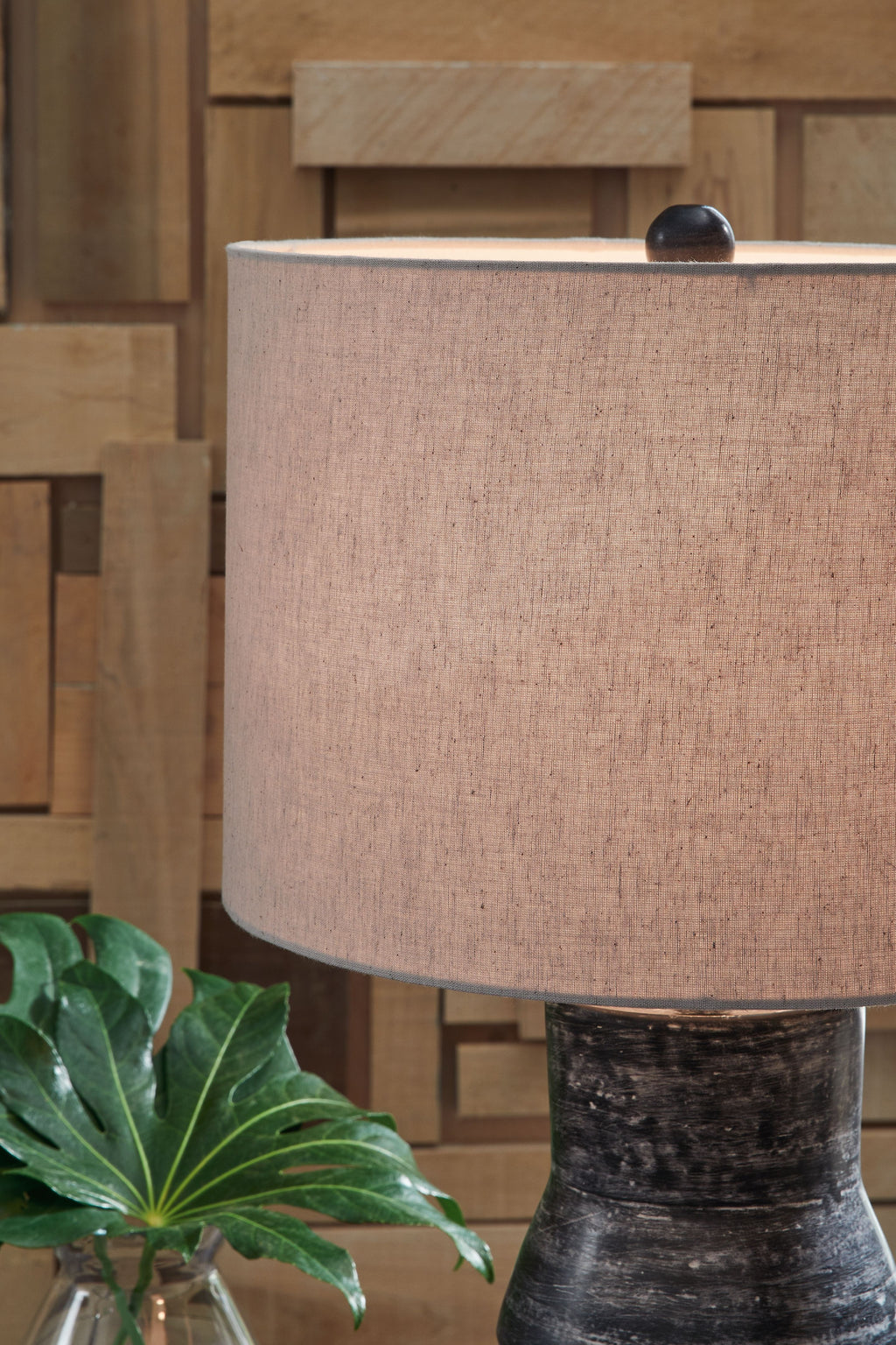 Beige drum shade on distressed black table lamp base, partially shown.