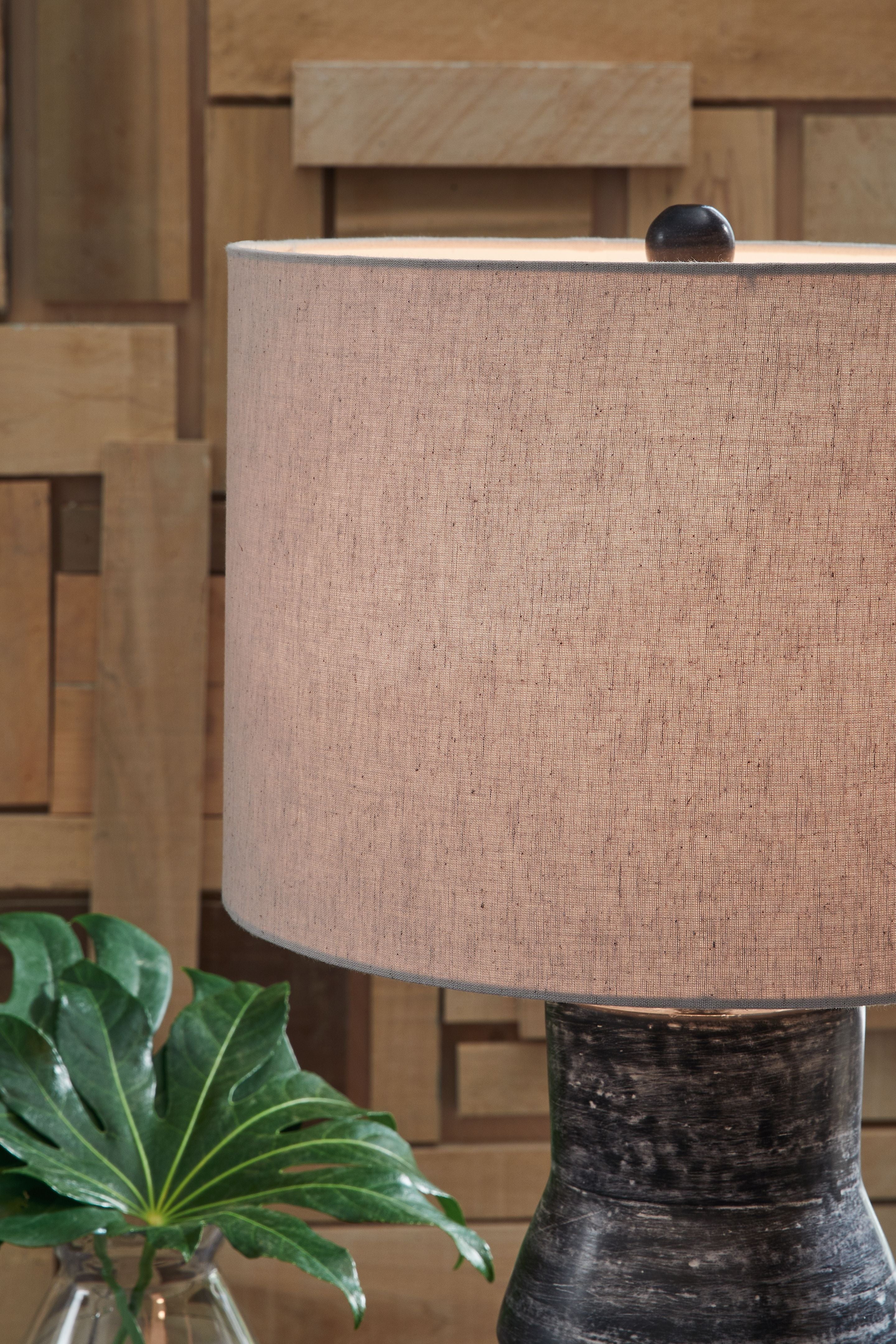 Beige drum shade on distressed black table lamp base, partially shown.