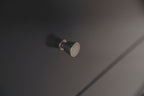 Round metal drawer knob on black dresser drawer front