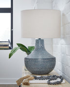 Metal table lamp with beige fabric drum shade and antique gray textured base