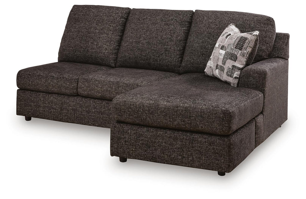 Dark charcoal sofa chaise with chaise ottoman, tufted seat, and patterned throw pillow