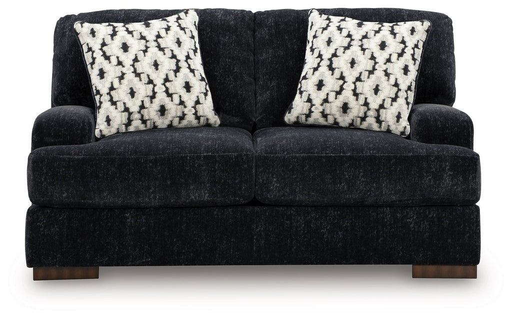 Dark charcoal loveseat with two black-and-white patterned throw pillows, wide seat
