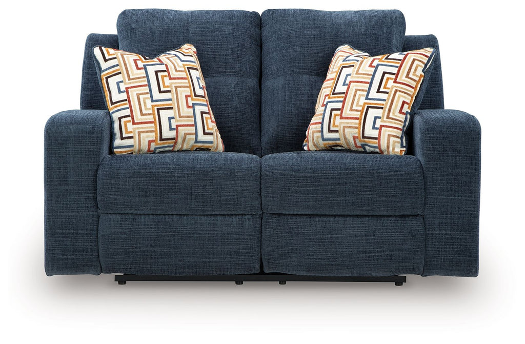 Blue reclining loveseat with two geometric patterned throw pillows