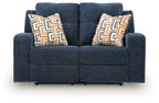 Blue reclining loveseat with two geometric patterned throw pillows