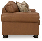 Caramel upholstered loveseat with attached back cushions and two patterned pillows