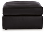 Black upholstered ottoman with rounded top and stitched paneling