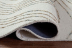 Deenbury rug corner shows folded pile over dark backing, off-white with swirl lines