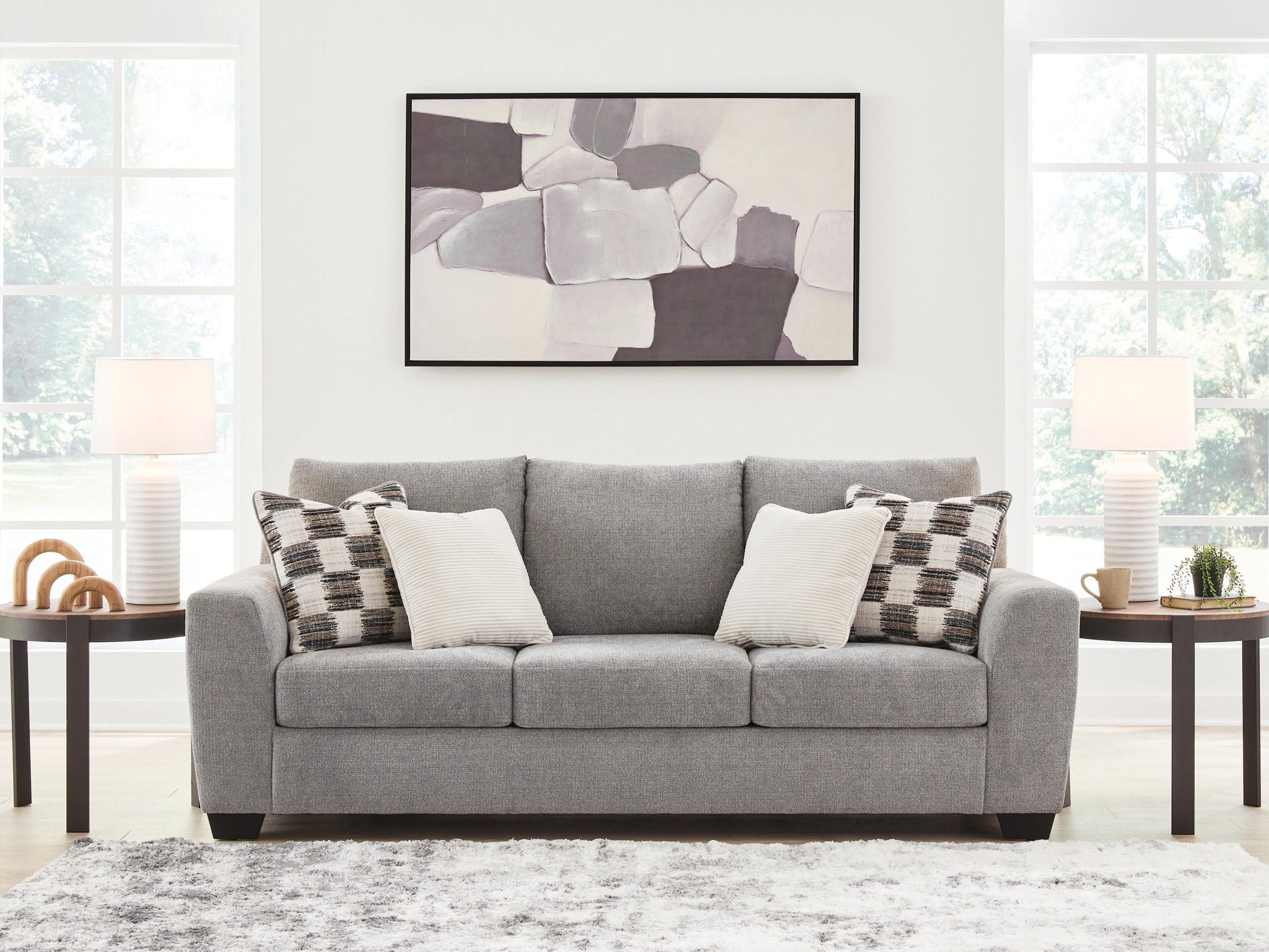 Gray fabric sofa with three seat cushions and check-pattern and cream pillows, wide view