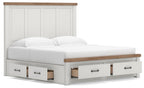 White panel storage bed with wood-trim top and three front pull-out drawers, angled view