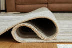 Corrbell rug corner rolled to show underside and low-pile texture.