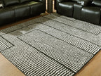 Black-and-white geometric striped rug with contrasting framed square motifs.