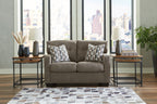 Dark brown loveseat with two patterned throw pillows centered on the sofa