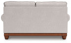 Upholstered loveseat back view with two top cushions and wooden base in light sand