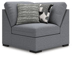 Gray upholstered wedge armchair with back cushions and zigzag throw pillow
