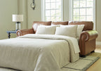 Caramel queen sofa sleeper with rolled arms and beige pillows in a sofa bed setup
